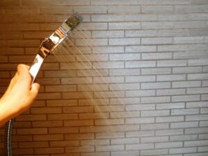 シャワーで壁の汚れを掃除する。